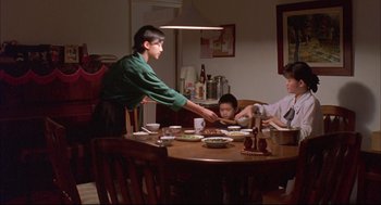 Movie still from “Yi Yi” (2000), directed by Edward Yang – Three people sitting at a dining room table eating; Medium shot, High angle