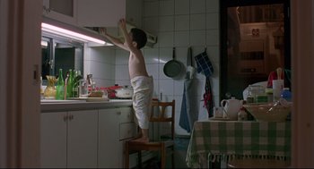 Movie still from “Yi Yi” (2000), directed by Edward Yang – A young boy standing on top of a chair in a kitchen; Wide shot, Low angle