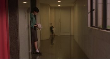 Movie still from “Yi Yi” (2000), directed by Edward Yang – A woman holding a stuffed animal in a hallway; Wide shot, High angle