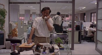 Movie still from “Yi Yi” (2000), directed by Edward Yang – A man talking on a phone in an office setting; Medium shot, High angle