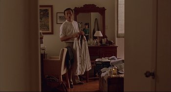 Movie still from “Yi Yi” (2000), directed by Edward Yang – A man standing in front of a mirror holding a shirt; Medium shot, Over the shoulder angle