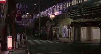 Movie still from “Yi Yi” (2000), directed by Edward Yang – A city street at night lit up by streetlights; Extreme Wide shot, High angle
