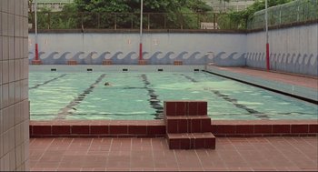 Movie still from “Yi Yi” (2000), directed by Edward Yang – A man swimming in a pool with a ramp leading up to it; Extreme Wide shot, High angle