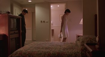 Movie still from “Yi Yi” (2000), directed by Edward Yang – A woman in a white dress standing next to a bed in a hotel room; Wide shot, Low angle