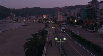 Movie still from “Yi Yi” (2000), directed by Edward Yang – People walking down a sidewalk at night near a beach; Extreme Wide shot, High angle