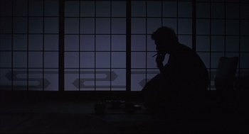 Movie still from “Yi Yi” (2000), directed by Edward Yang – A man sitting on the floor smoking a cigarette; Wide shot, Low angle