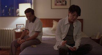 Movie still from “Yi Yi” (2000), directed by Edward Yang – A man and a woman sitting on a bed playing a video game; Medium shot, Low angle