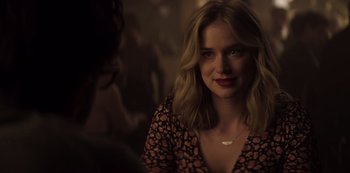 Movie still from “You” (2018), created by Sera Gamble – A beautiful young woman with blonde hair wearing a black and red dress; Close Up shot, Over the shoulder angle