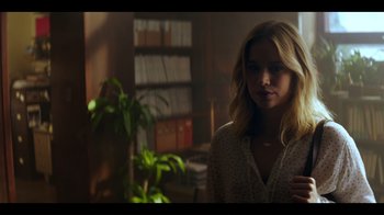 Movie still from “You” (2018), created by Sera Gamble – A woman standing in front of a book shelf; Medium shot, Over the shoulder angle