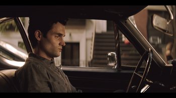 Movie still from “You” (2018), created by Sera Gamble – A man sitting in the driver's seat of a car; Close Up shot, High angle