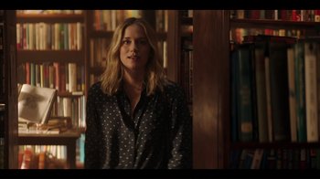 Movie still from “You” (2018), created by Sera Gamble – A woman standing in front of bookcases in a library; Medium shot, Over the shoulder angle
