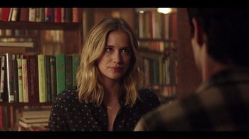 Movie still from “You” (2018), created by Sera Gamble – A woman in a black polka dot shirt is in a library; Close Up shot, Over the shoulder angle
