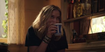 Movie still from “You” (2018), created by Sera Gamble – A woman drinking a cup of coffee in a room; Close Up shot, Over the shoulder angle