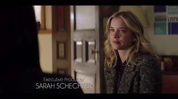 Movie still from “You” (2018), created by Sera Gamble – A young woman is standing in front of a door; Medium shot, Over the shoulder angle