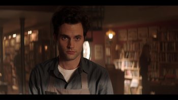 Movie still from “You” (2018), created by Sera Gamble – A man in a striped shirt is looking at the camera; Close Up shot, Over the shoulder angle