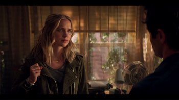 Movie still from “You” (2018), created by Sera Gamble – A woman standing in front of a window in a room; Medium shot, Over the shoulder angle