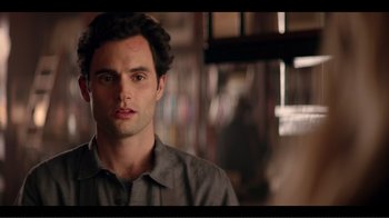 Movie still from “You” (2018), created by Sera Gamble – A person wearing a gray shirt; Close Up shot, Over the shoulder angle