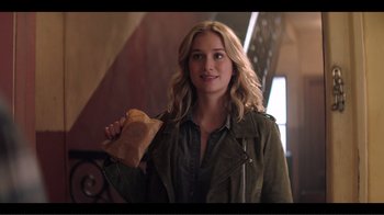 Movie still from “You” (2018), created by Sera Gamble – A woman holding a piece of bread in her hand; Medium shot, Over the shoulder angle