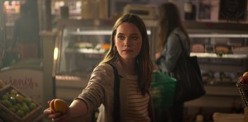 Movie still from “You” (2018), created by Sera Gamble – A woman holding an orange in her right hand; Medium shot, Over the shoulder angle