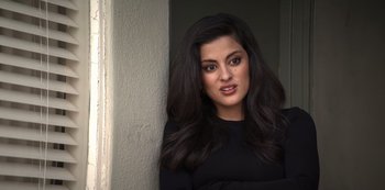 Movie still from “You” (2018), created by Sera Gamble – A woman with long black hair leaning up against a wall; Close Up shot, Over the shoulder angle