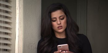 Movie still from “You” (2018), created by Sera Gamble – A beautiful young lady looking at a cell phone; Close Up shot, Low angle