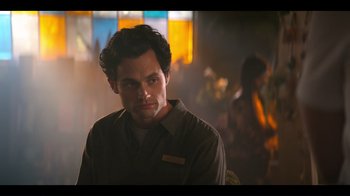 Movie still from “You” (2018), created by Sera Gamble – A man in a brown shirt is looking at the camera; Close Up shot, Over the shoulder angle