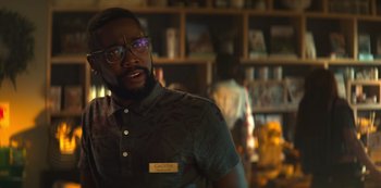 Movie still from “You” (2018), created by Sera Gamble – A man with glasses is standing in front of a bookshelf; Close Up shot, Over the shoulder angle