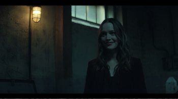 Movie still from “You” (2018), created by Sera Gamble – A woman standing next to a window in a dark room; Medium shot, Over the shoulder angle