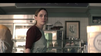 Movie still from “You” (2018), created by Sera Gamble – A woman standing in front of a counter in a kitchen; Medium shot, Over the shoulder angle