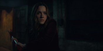 Movie still from “You” (2018), created by Sera Gamble – A young woman in a dark room looking at the camera; Medium shot, Low angle