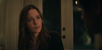 Movie still from “You” (2018), created by Sera Gamble – A woman sitting on a couch in front of a window; Close Up shot, Over the shoulder angle