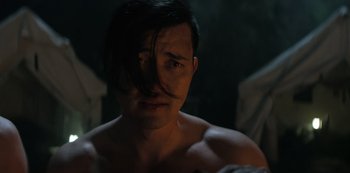 Movie still from “You” (2018), created by Sera Gamble – A shirtless man with long black hair looking at the camera; Close Up shot, Over the shoulder angle