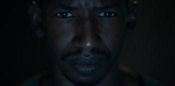 Movie still from “Archive 81” (2022), created by Rebecca Sonnenshine – A man's face in the dark; Extreme Close Up shot, High angle