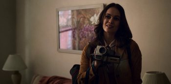 Movie still from “Archive 81” (2022), created by Rebecca Sonnenshine – A woman is holding a camera in a room; Close Up shot, Over the shoulder angle