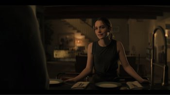 Movie still from “You” (2018), created by Sera Gamble – A woman sitting at a table with a plate of food; Medium shot, Over the shoulder angle
