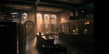 Movie still from “You” (2018), created by Sera Gamble – A room filled with lots of bookshelves and tables; Extreme Wide shot, Low angle