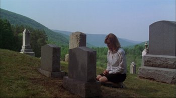 Movie still from “You Can Count on Me” (2000), directed by Kenneth Lonergan – A woman sitting on the ground in front of a grave yard; Wide shot, High angle