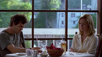 Movie still from “You Can Count on Me” (2000), directed by Kenneth Lonergan – Two people sitting at a table with a basket of food in front of a window; Medium shot, Over the shoulder angle