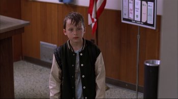 Movie still from “You Can Count on Me” (2000), directed by Kenneth Lonergan – A boy in a black and white jacket standing in front of a flag; Medium shot, Low angle