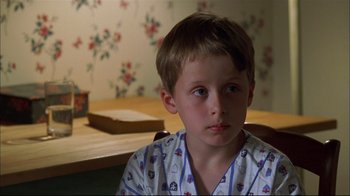 Movie still from “You Can Count on Me” (2000), directed by Kenneth Lonergan – A young boy wearing pajamas sitting at a wooden table; Close Up shot, High angle