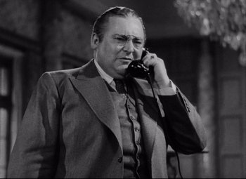Movie still from “You Can't Take It with You” (1938), directed by Frank Capra – An older man talking on a phone while wearing a suit and tie; Close Up shot, Low angle