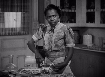 Movie still from “You Can't Take It with You” (1938), directed by Frank Capra – An old photo of a woman preparing food in a kitchen; Medium shot, High angle