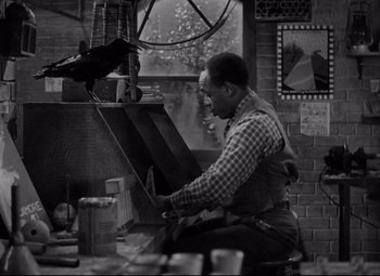 Movie still from “You Can't Take It with You” (1938), directed by Frank Capra – A black and white photo of a man working on an object; Medium shot, High angle