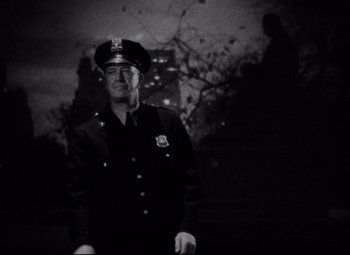 Movie still from “You Can't Take It with You” (1938), directed by Frank Capra – A man in a police uniform standing in front of a building; Medium shot, Low angle
