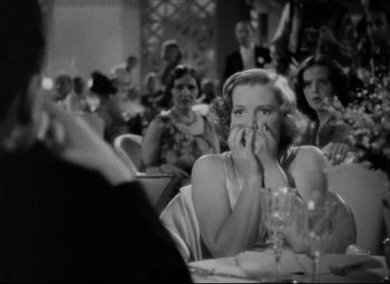 Movie still from “You Can't Take It with You” (1938), directed by Frank Capra – A black - and - white photo of a woman sitting at a table; Medium shot, Over the shoulder angle
