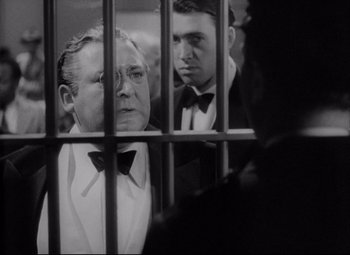 Movie still from “You Can't Take It with You” (1938), directed by Frank Capra – A man in a suit and bow tie in front of another man in a suit and bow tie in front of another man; Close Up shot, Low angle