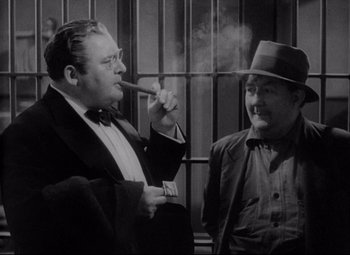 Movie still from “You Can't Take It with You” (1938), directed by Frank Capra – A man smoking a cigar next to another man in front of a cage; Medium shot, Low angle