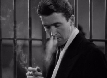Movie still from “You Can't Take It with You” (1938), directed by Frank Capra – A black and white photo of a man smoking a cigarette; Close Up shot, Low angle