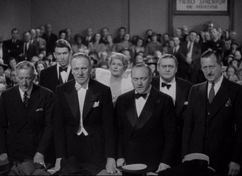 Movie still from “You Can't Take It with You” (1938), directed by Frank Capra – A black and white photo of a group of men in tuxedos; Medium shot, High angle