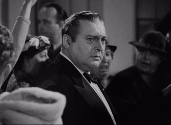 Movie still from “You Can't Take It with You” (1938), directed by Frank Capra – An old photo of a man in a suit and tie; Close Up shot, Over the shoulder angle